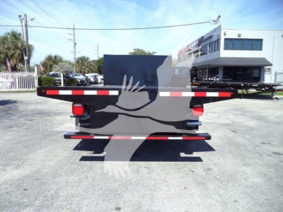 Flatbed truck rear view showing '2011 Ford E450' with a black flatbed and red tail lights, two white and red reflective stripes along the edges, and a building in the background.