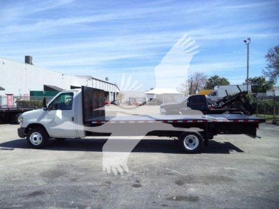 Flatbed tow truck side view showing white Ford E-450 with long flatbed and lettering along side.