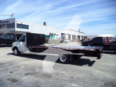 Flatbed tow truck 2011 Ford E450 with long flatbed in service, side view showing cab and flatbed in a dealership lot.