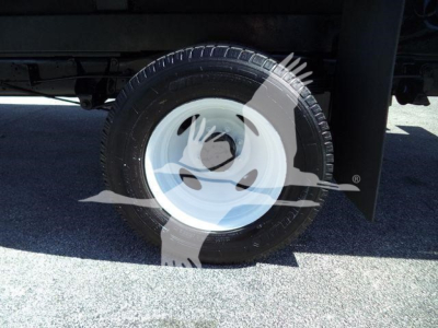 Ford E450 flatbed truck wheel and tire visible under chassis, white steel rim with black tire.