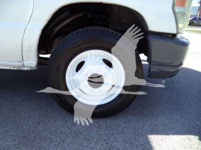 Ford E450 front wheel and fender showing steel white wheel and part of black bumper.