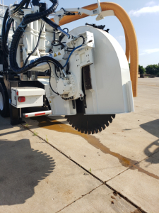 Front-angle view of a generator or rock-cutting attachment mounted on a Volvo VHD86B300 truck chassis showing a large circular saw blade and hydraulic hoses.