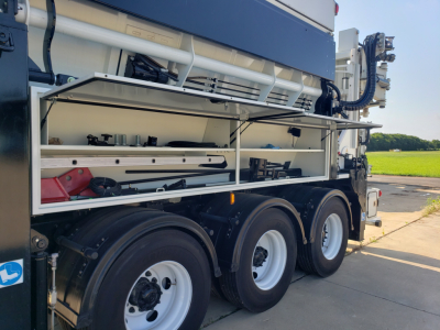 Volvo VHD86B300 truck side view showing open tool compartments with shelves and equipment, three rear axles, white wheel rims, and stacked components.