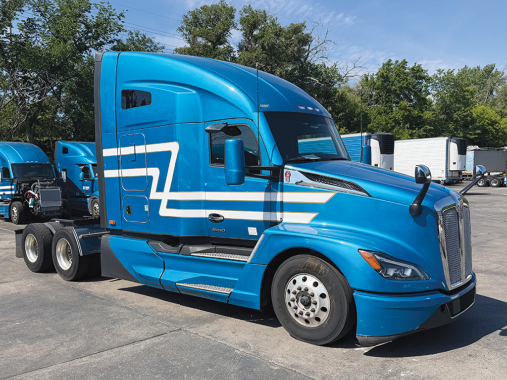 Blue Kenworth T680 Next Gen tractor-trailer cab side profile with white stripe accents.