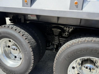 Dual rear axles with heavy-duty tires and exposed suspension components under a dump truck.