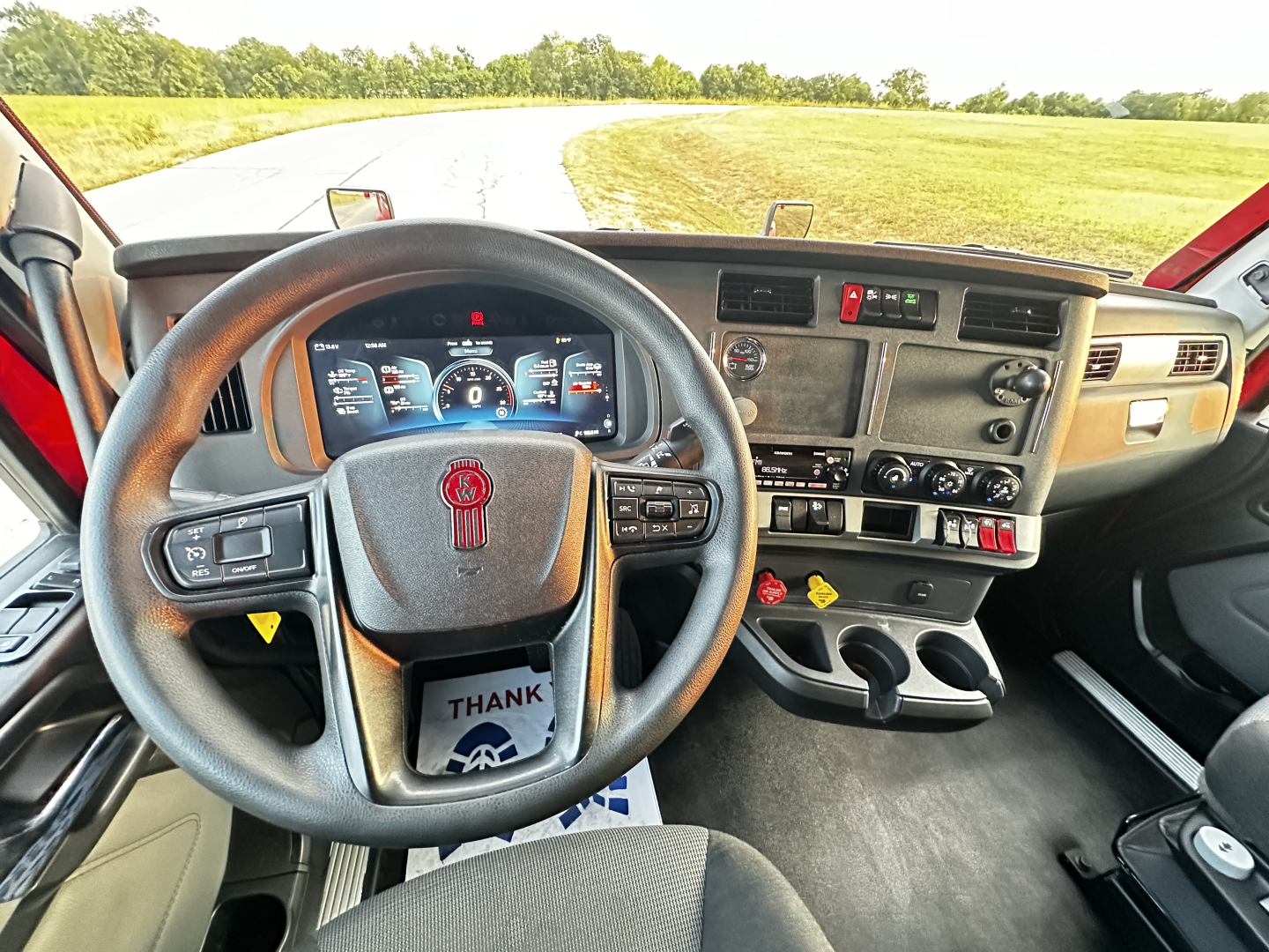Kenworth T680 dashboard and steering wheel interior showing digital gauges and controls.