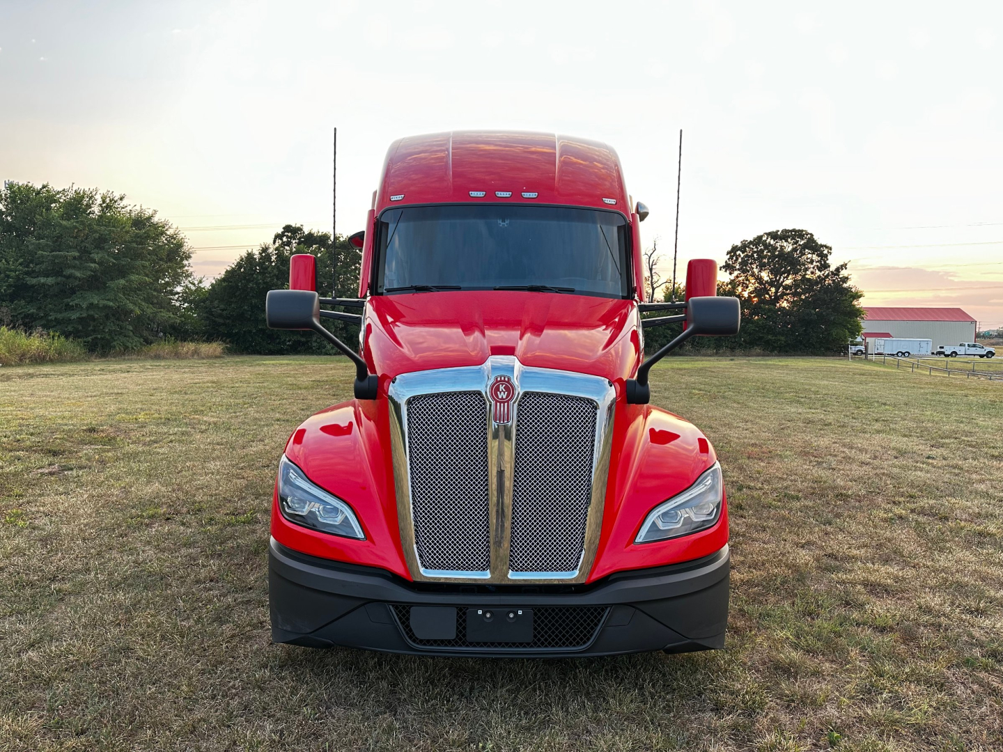 Kenworth T680 front view showing bold chrome grille and red cab, daylight exterior image.