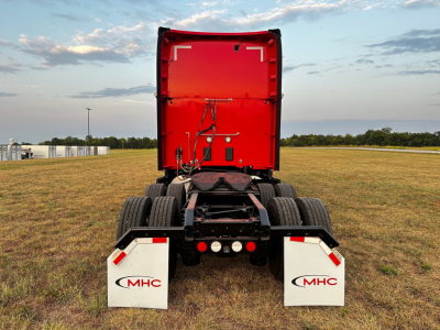 Rear view of a red Kenworth/T680 truck tractor with white MHC mud flaps, showing the back of the cab and chassis, no visible decals.
