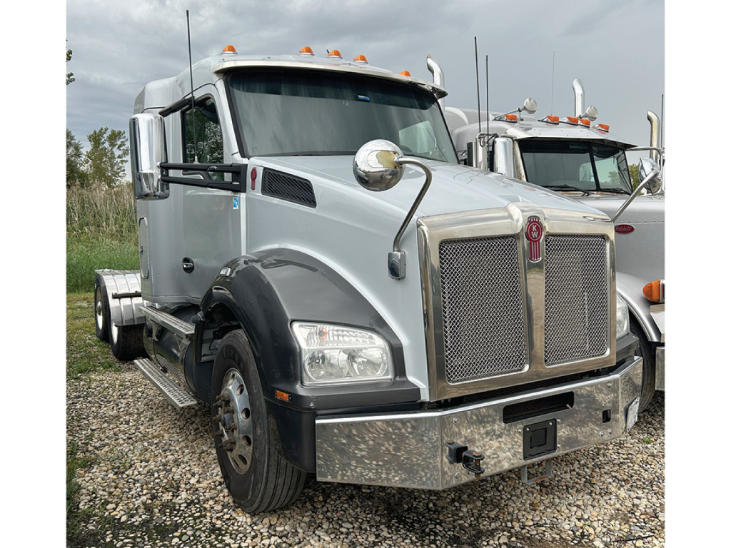 Kenworth T-880 conventional daycab truck in silver with large chrome grille and bumper, front view.