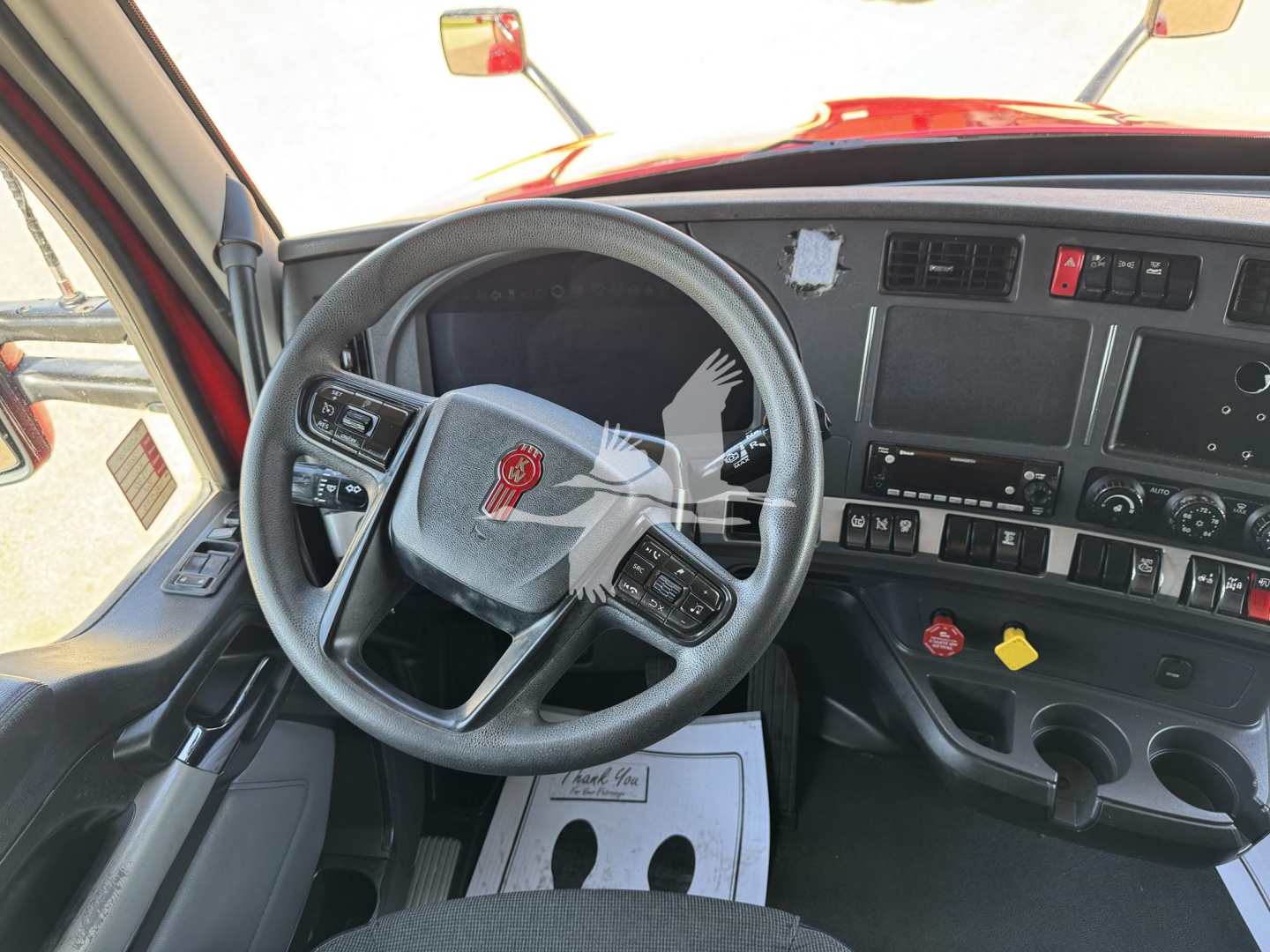 Kenworth T680 cab interior showing steering wheel and dashboard gauges and controls