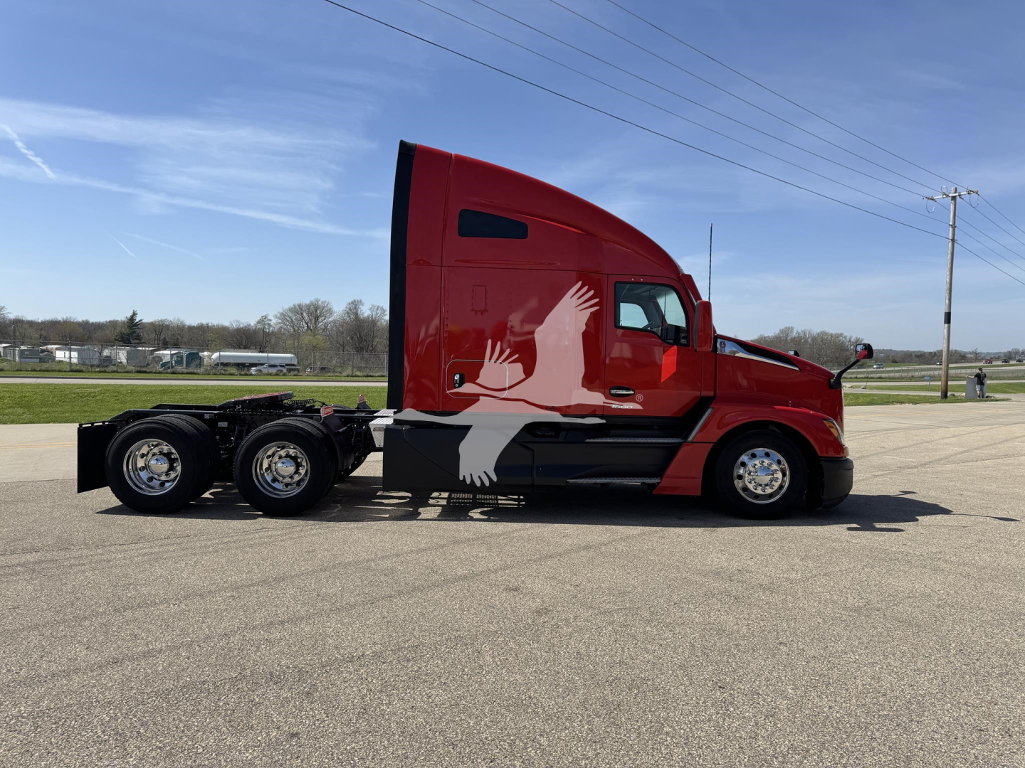 Kenworth T680 conventional sleeper truck side view showing long red cab with black chassis and dual rear axles.