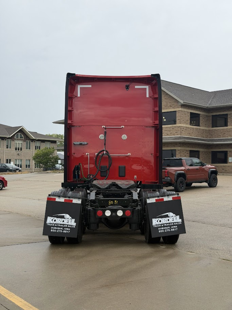 Back view of red Kenworth T680 sleeper cab tractor showing rear doors, bumper, and mudflaps with Kordell van decals. license plates not visible.