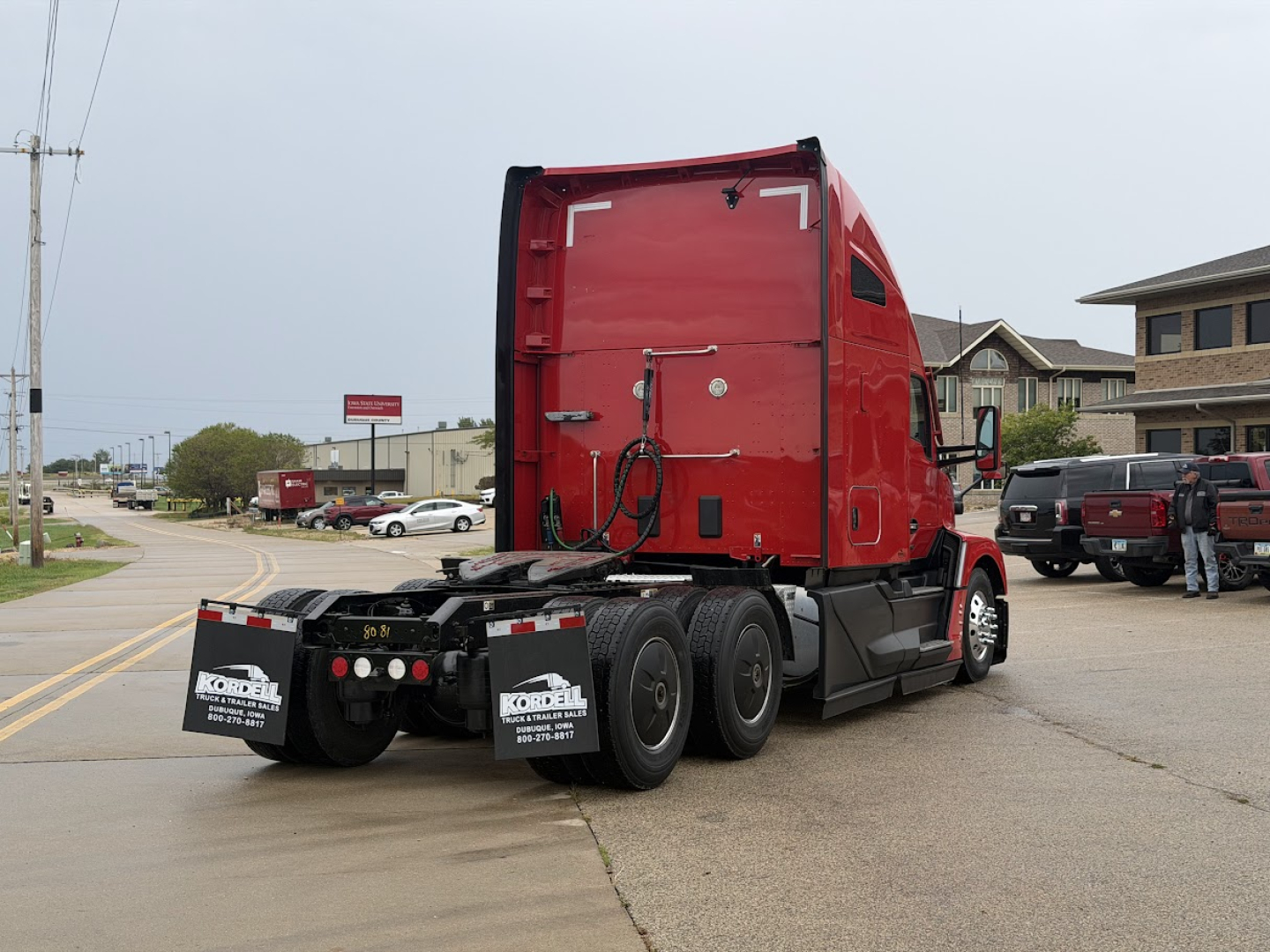 Kenworth T680 rear three-quarter view showing sleeper cab, red paint, dual rear axles, and trailer hitch area.