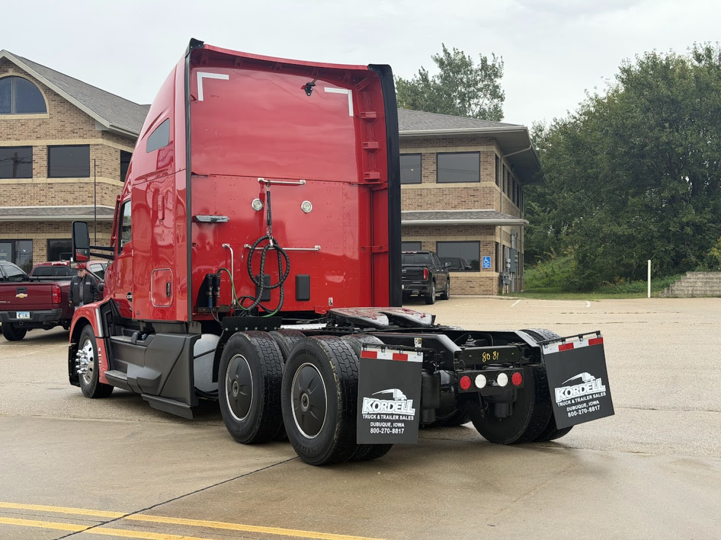 Kenworth T680 tractor in red with sleeper cab, rear view showing dual rear axles and bumper area, no visible serials text.