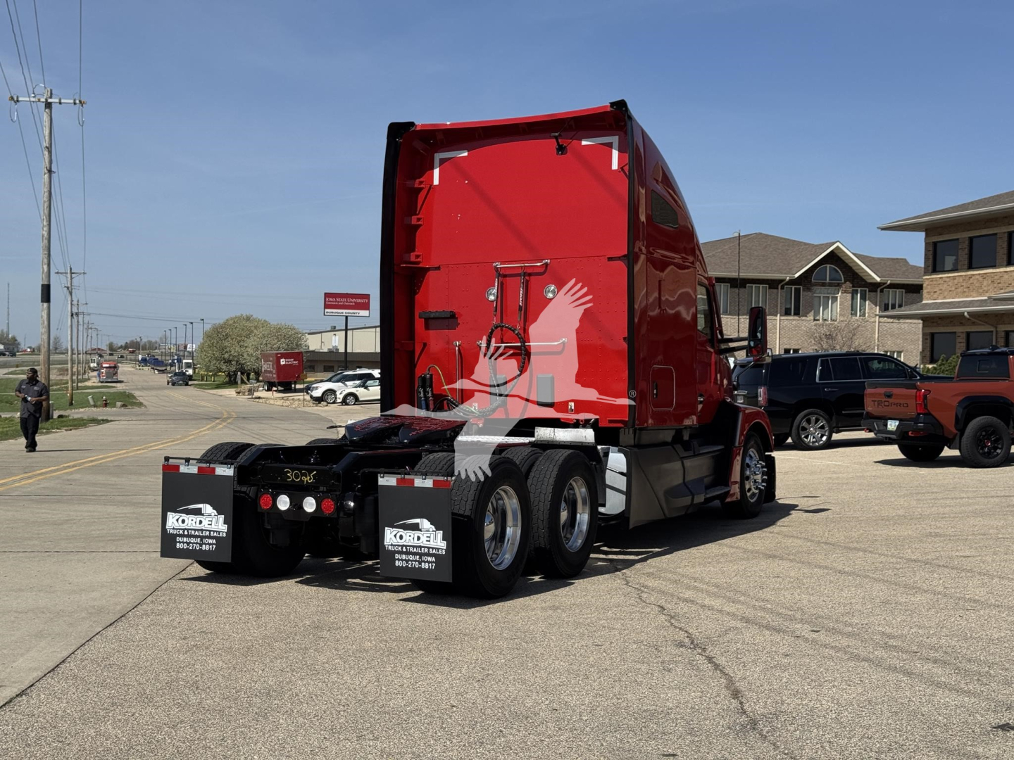 Kenworth T680 truck rear view showing red sleeper cab and chassis, dual rear axles, and stock numbers.