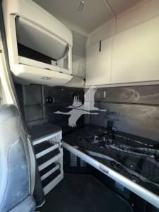 Kenworth T680 cab interior showing sleeper area with storage cabinet and ladder, side paneling and step area visible.