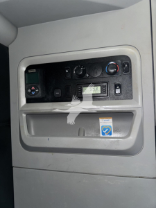 Kenworth truck dashboard area in sleeper cab showing control panel with gauges and a small digital display, plus a storage pocket and a blue sticker.