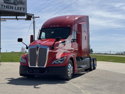 Kenworth T680 tractor-trailer in red, front three-quarter view, with tall sleeper cab and dual rear axles, highway in background.