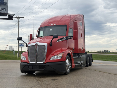 Red Kenworth T680 truck in a parking lot with a large chrome grille and dual mirrors; front-left view shows aggressive headlights.