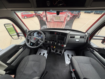Kenworth T680 cab interior view showing steering wheel dashboard instrumentation and front seats.