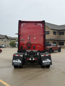 Back view of red Kenworth T680 sleeper cab tractor showing rear doors, bumper, and mudflaps with Kordell van decals. license plates not visible.