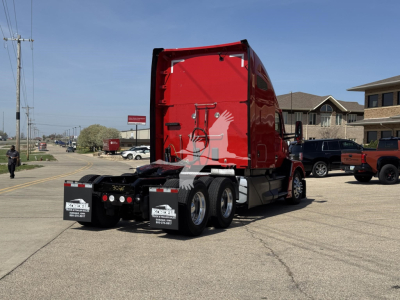 Kenworth T680 truck rear view showing red sleeper cab and chassis, dual rear axles, and stock numbers.