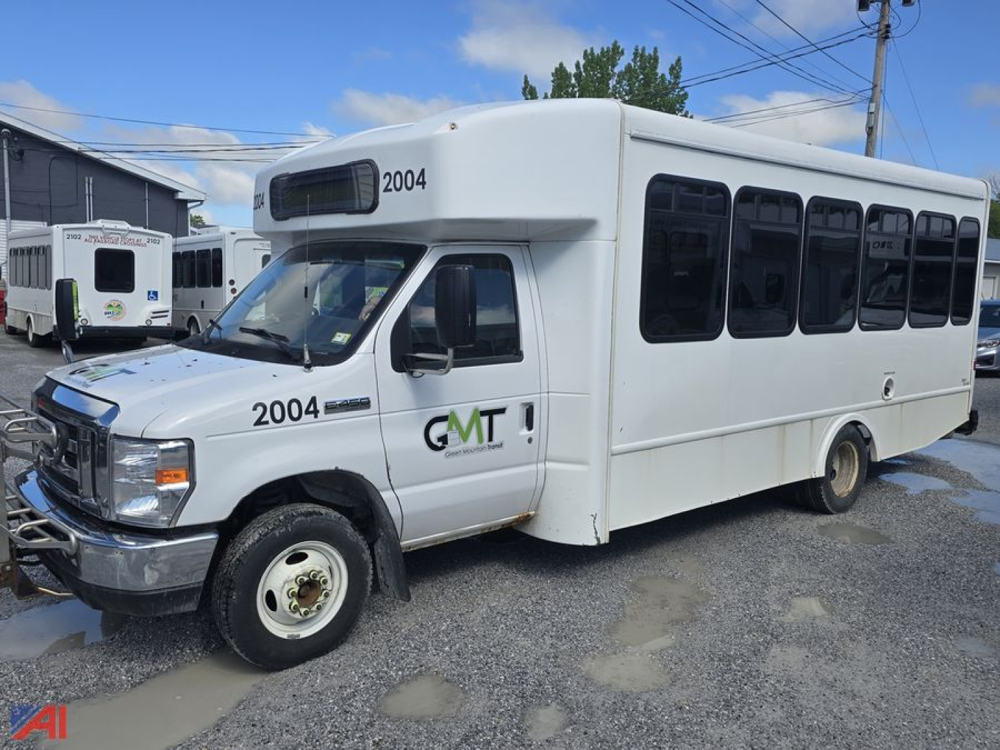 Ford E450 wheelchair bus side view showing driver door and GM Transit logo, number 2004 on hood and side window, white body, medium-length bus