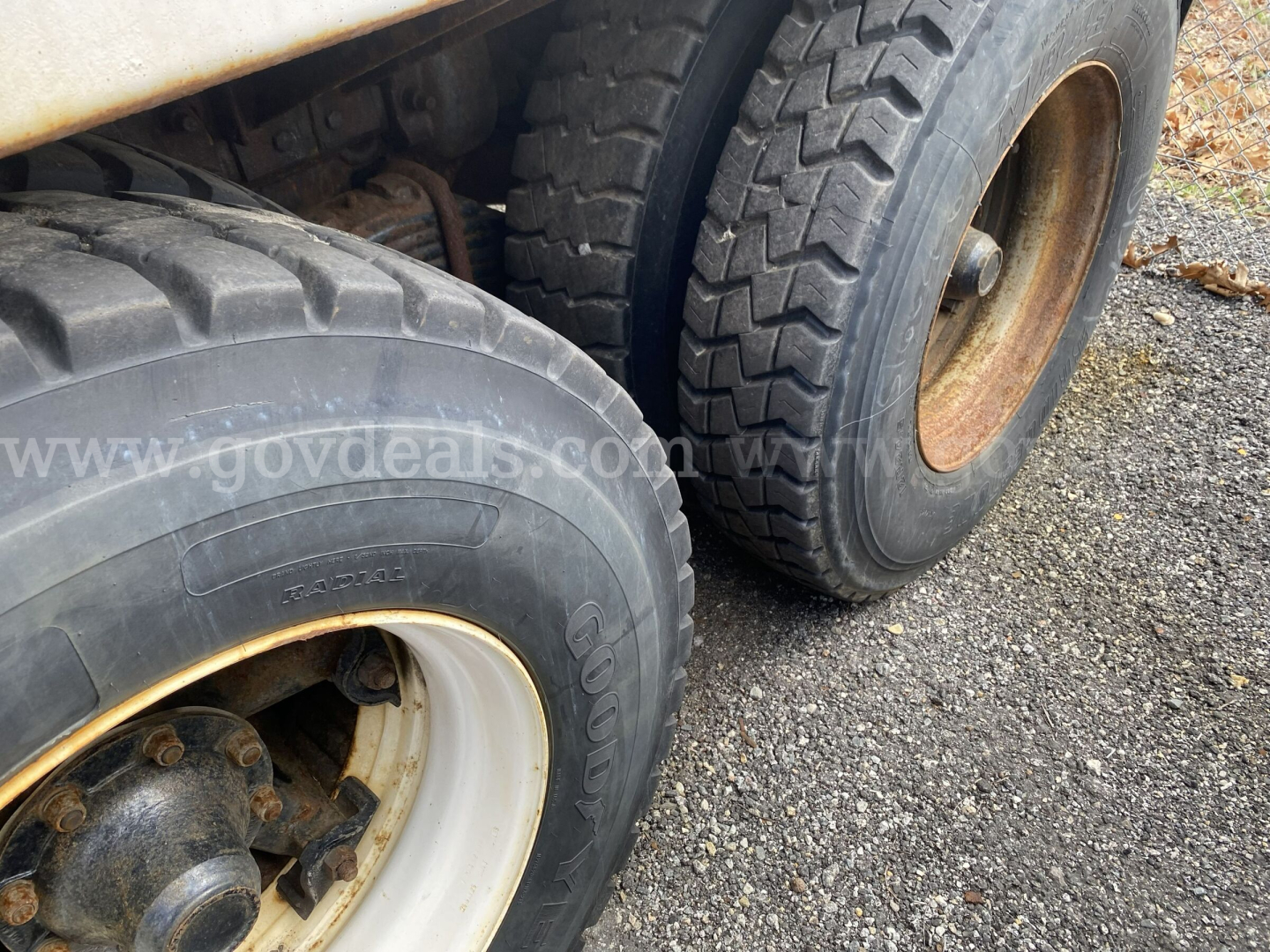 Dump truck wheel overview showing dual rear axles with large Goodyear tires and tan rims on a Mack GU713.