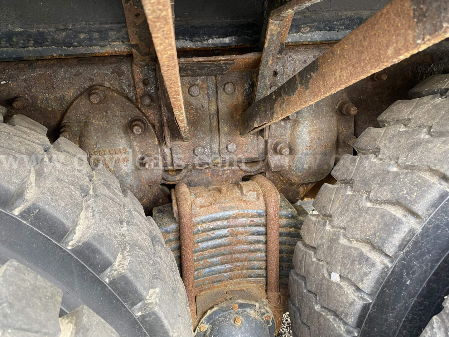 Mack GU713 truck undercarriage showing differential housing and leaf spring suspension between dual rear tires.