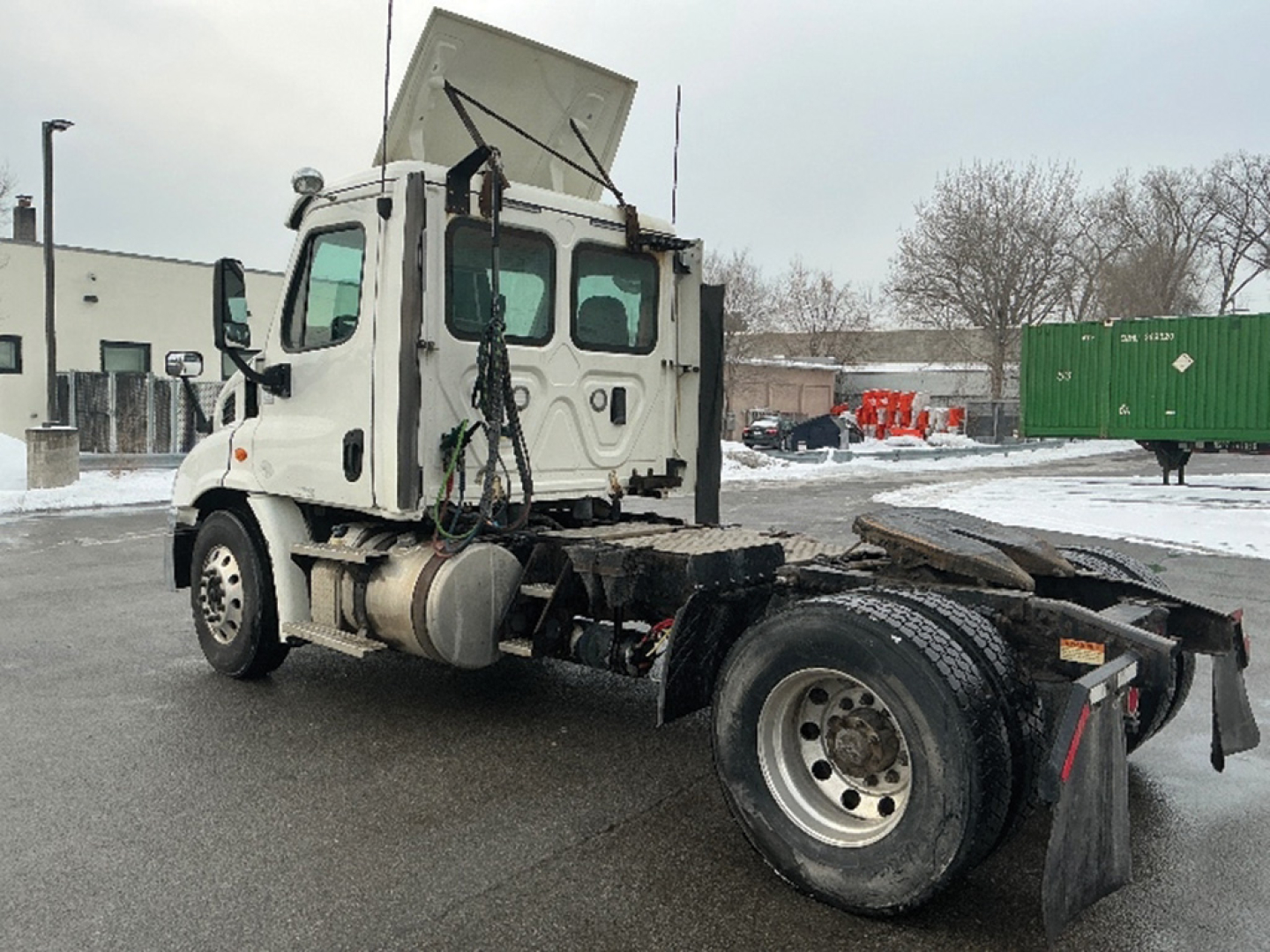 Freightliner Cascadia113 cab-forward truck in a lot showing side view with open hood and rear chassis; wheel and diagnostic components visible.