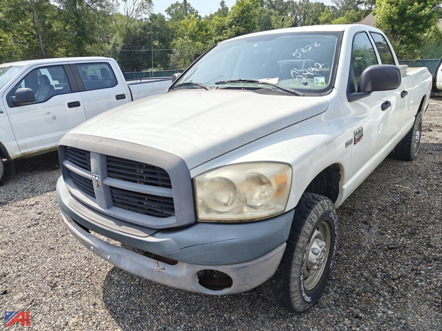 Dodge Ram 2500 pickup truck in front view showing front grille, headlights, and bumper, white exterior with black mirrors and tires in a gravel lot.