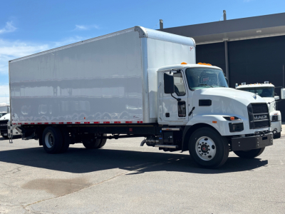 Box truck in showroom lot showing 2026 Mack MD6 with white cab and large box cargo area.