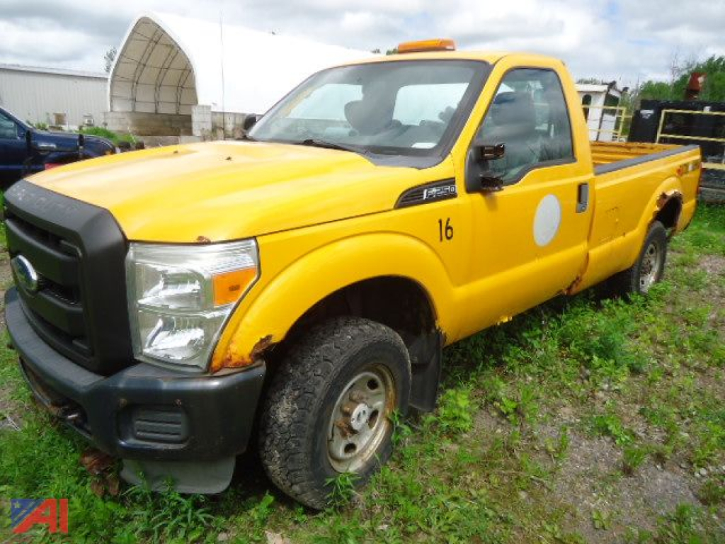 Ford F-250 Super Duty pickup truck in yellow, single cab, 4x4, with black bumper and round white door decal, parked on grassy lot.