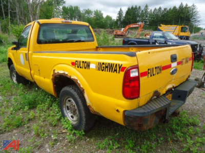 2011 Ford F-250 Super Duty pickup truck in yellow with Fulton Highway decals on rear quarter and tailgate, visible damage on rear bumper and wheel well.