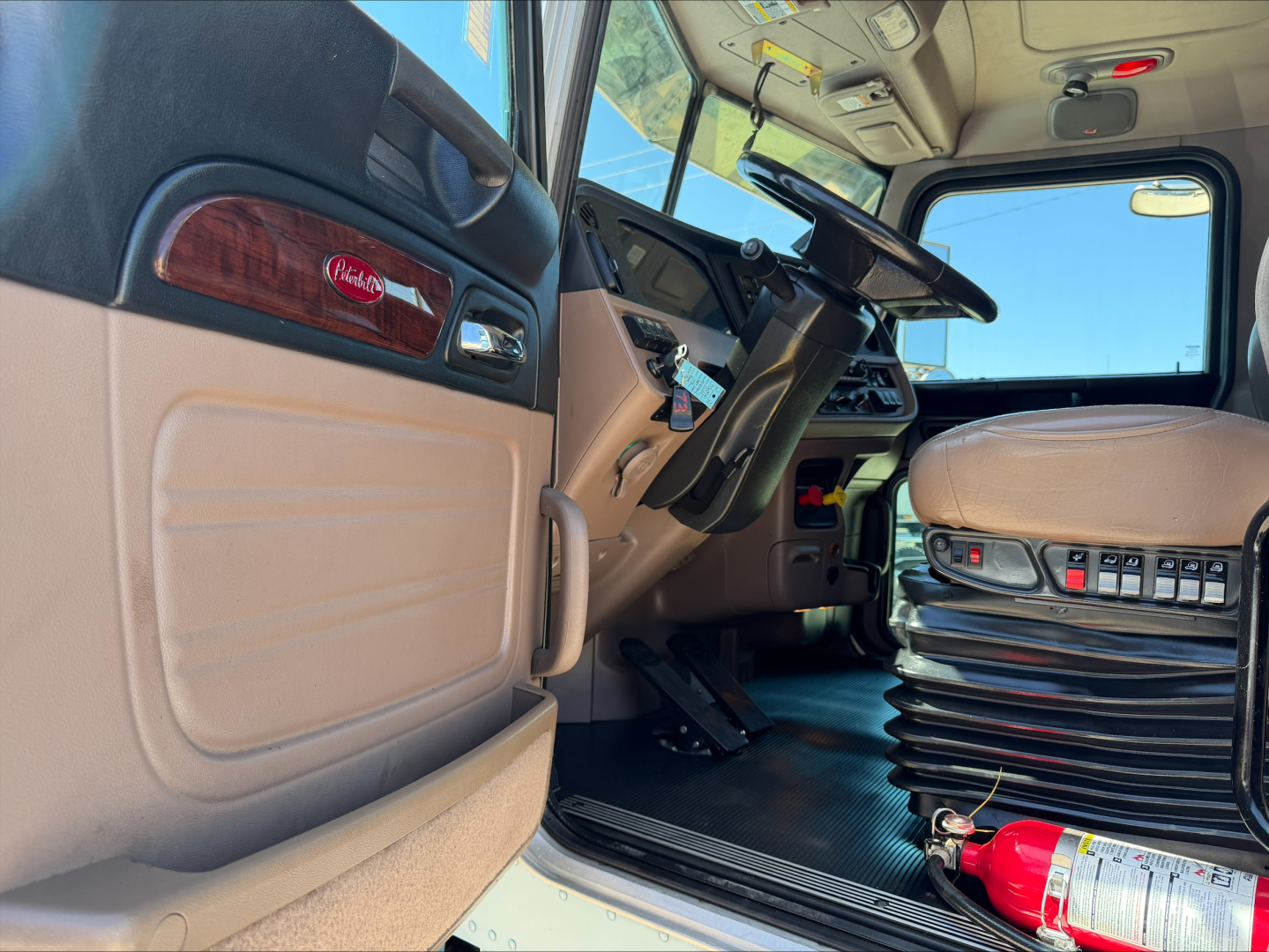 Peterbilt 389 truck interior and cab floor with steering wheel, driver seat, and fire extinguisher visible.