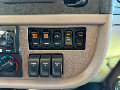 Truck dash panel with multiple switches labeled TRUCK LOCK, TRUCK GATE, AIR FLAPS, OPEN TRUCK TARP, CLOSE etc., plus spare A-D switches visible.