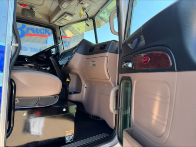 Peterbilt 389 truck interior cab view with steering wheel and dashboard; tan and black accents visible; entry door open.