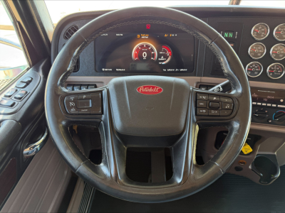 Peterbilt steering wheel and dashboard with digital gauge cluster and multiple gauges; steering wheel center badge reads Peterbilt.