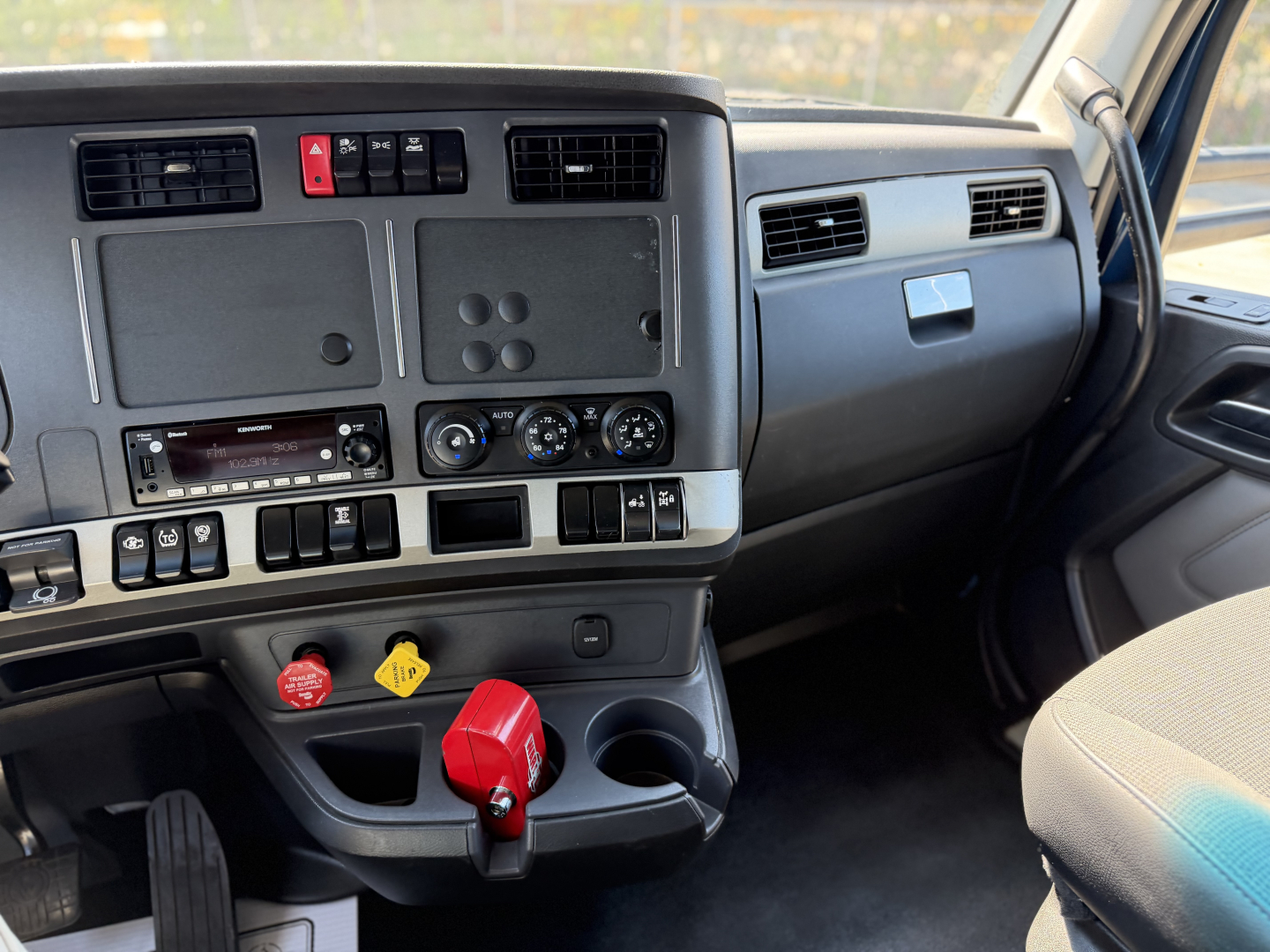 Kenworth T680 cab interior showing dashboard controls and red trailer air supply knob.