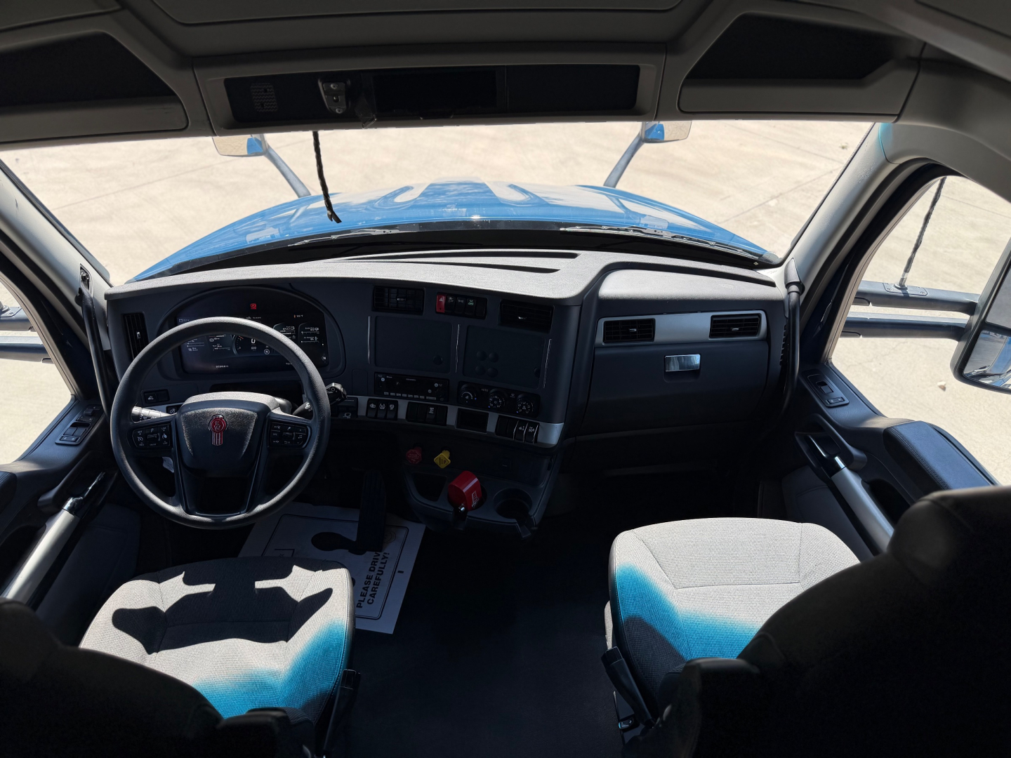 Interior of Kenworth T680 cab showing steering wheel and dashboard with controls.