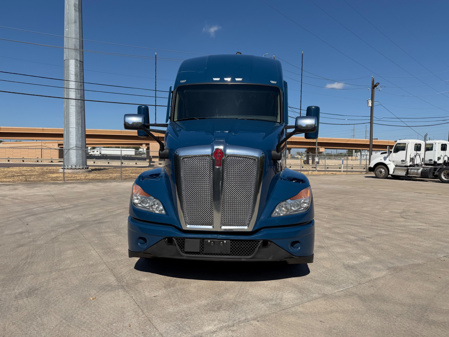 Front view of a blue 2023 Kenworth T680 truck showing grille, headlights, and large front bumper.
