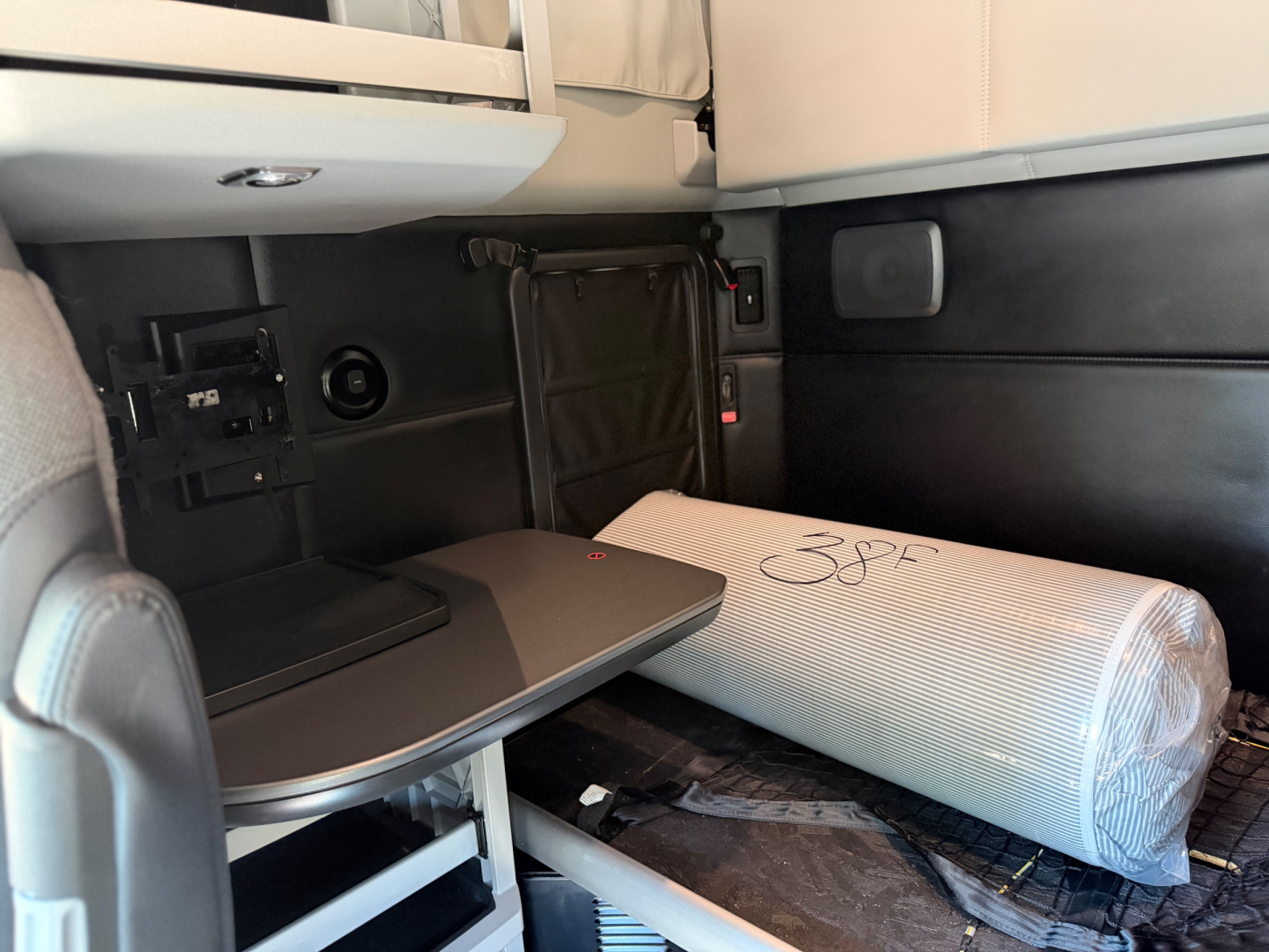 Kenworth T680 interior showing sleeper with fold-out countertop and plastic-wrapped cushion.