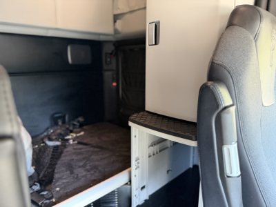 Kenworth T680 interior cab area showing sleeper storage cabinet and fold-out step with seating in foreground.