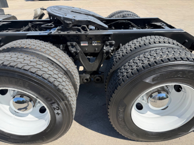 Dual rear axle on a Kenworth truck chassis showing tires and suspension components; no legible model text visible on tires or nearby labels.