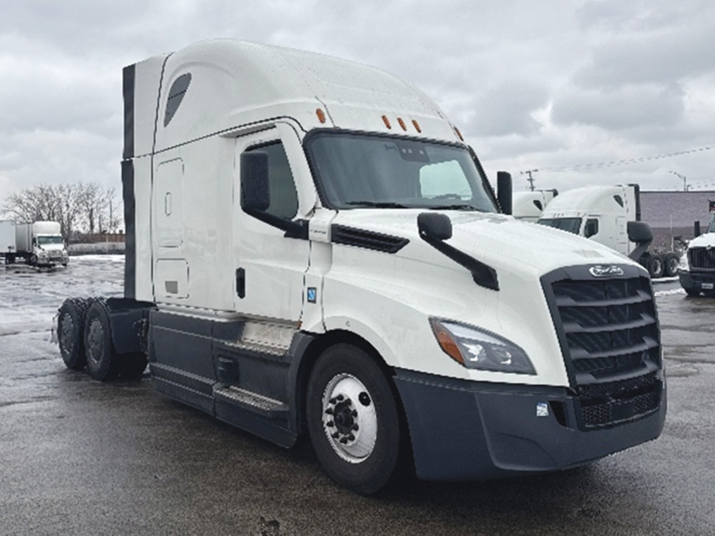 Freightliner Cascadia126 truck in a lot, front-side view showing sleeper cab, white exterior, black bumper and grille.
