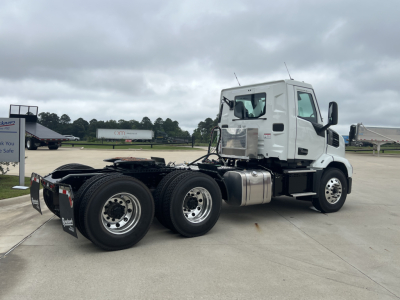 Mack AN64T conventional daycab tractor side view showing dual rear axles with fuel tanks, white cab, and chrome wheels.
