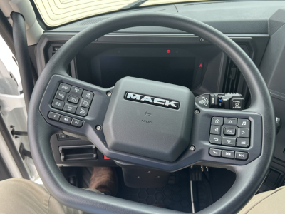 Mack AN64T truck interior steering wheel with multiple control buttons, dash display, and Mack logo at center.