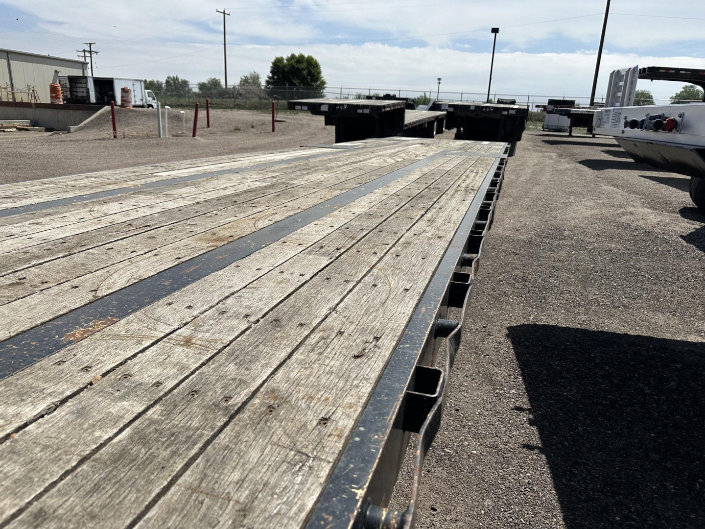 Great Dane spread air drop deck trailer showing wooden deck planks and steel side rails with landing gear in background.