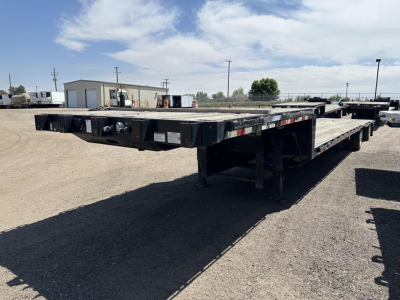 Great Dane spread air drop deck trailer showing long flatbed with low-clearance, black paint, reflective safety stripes along sides.