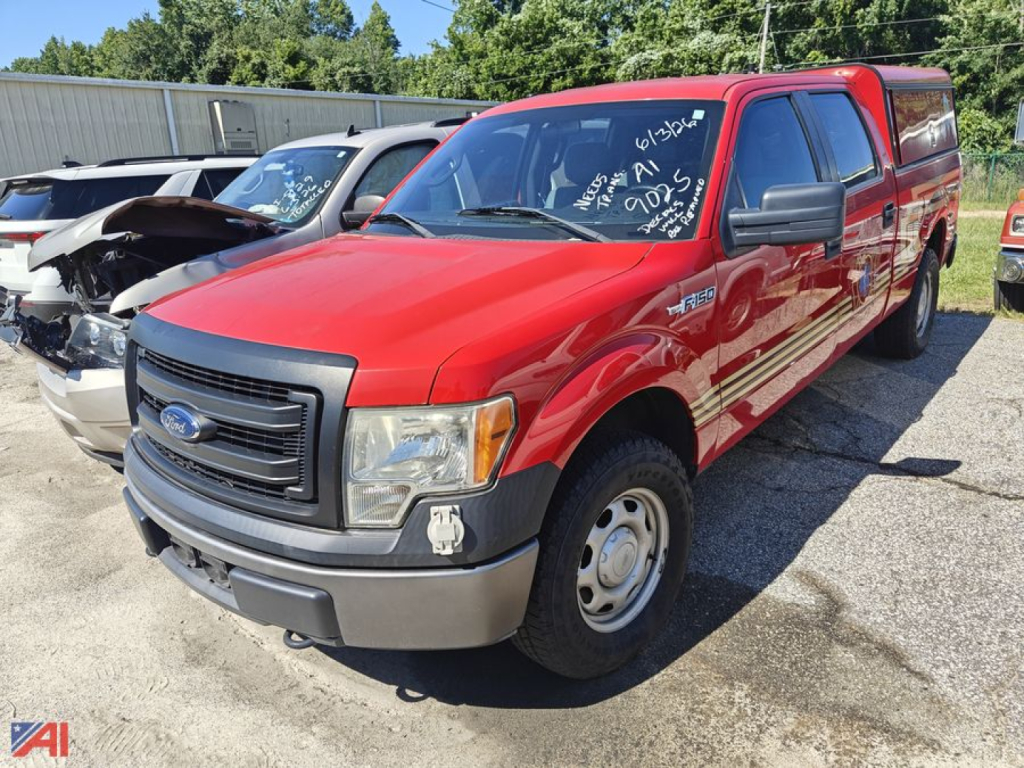 Ford F-150 emergency pickup truck red crew cab with cap, front grille, side mirrors, and writing on windshield, in a vehicle lot.